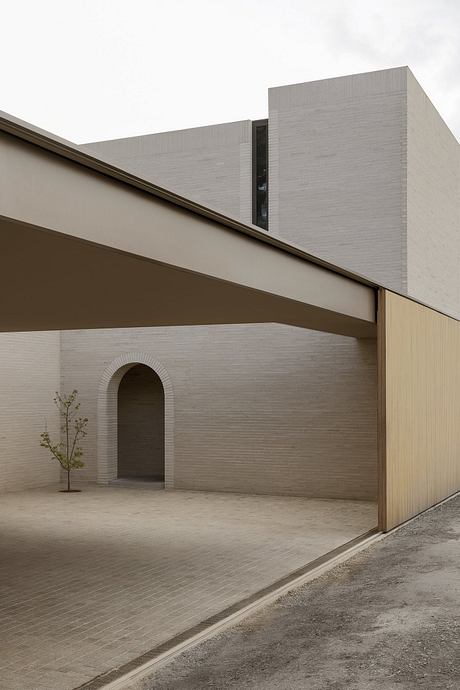 Minimalist architectural design featuring textured walls, arched entryway, and modern siding.