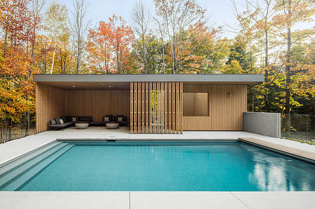 Contemporary pool house with sleek wooden exterior and integrated seating area.