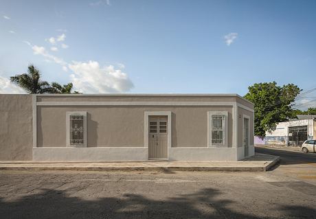 A single-story building with a gray exterior, barred windows, and a centrally located entrance door.