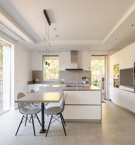 Modern, minimalist kitchen with clean lines, sleek cabinetry, and a centralized island. Abundant natural light and neutral tones create a serene atmosphere.