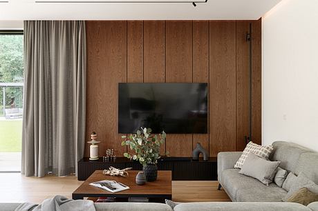Cozy living room with wood-paneled walls, large TV, and minimalist furniture.