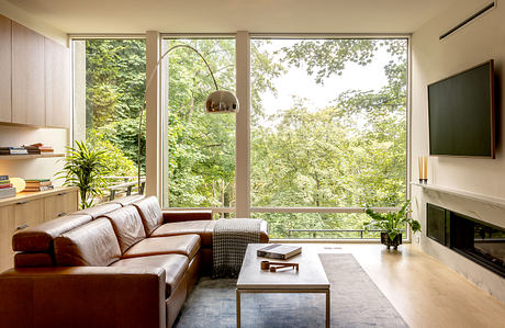 Spacious living room with floor-to-ceiling windows, modern furnishings, and nature-inspired decor.