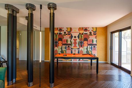 Vibrant mid-century modern interior with geometric mural, wooden floors, and metal columns.