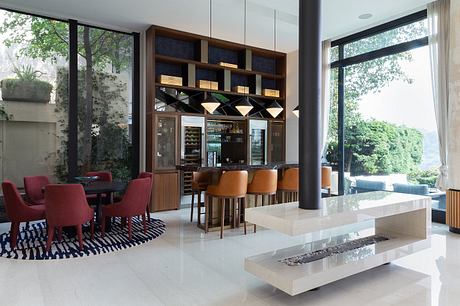 Sleek, modern interior with wood-paneled bar, red chairs, and large windows overlooking greenery.