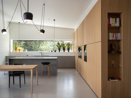 Spacious kitchen with sleek gray cabinets, wooden accents, and modern pendant lighting.
