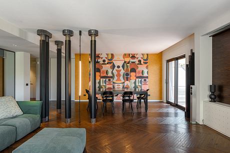 A modern, open-concept living space with bold geometric artwork, wood floors, and minimalist furnishings.