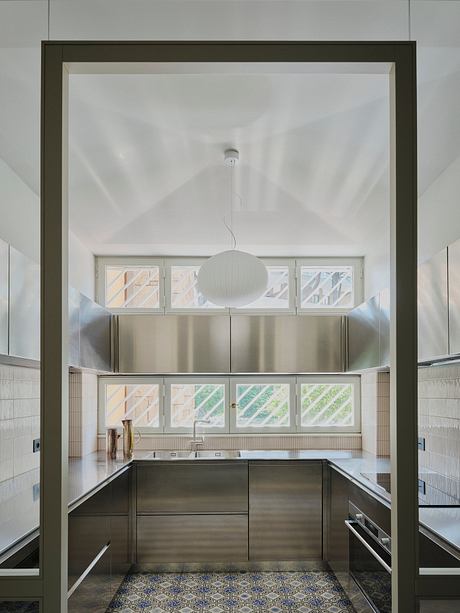 Modern kitchen with sleek stainless steel appliances, geometric tile floor, and pendant lighting.