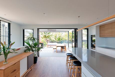 Bright, open-concept kitchen and living area with wooden accents and lush outdoor views.