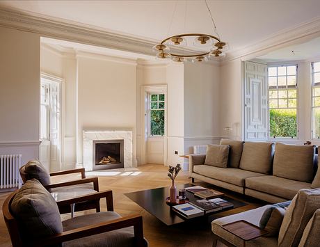Elegant living room with ornate moldings, fireplace, and a chandelier illuminating the space.