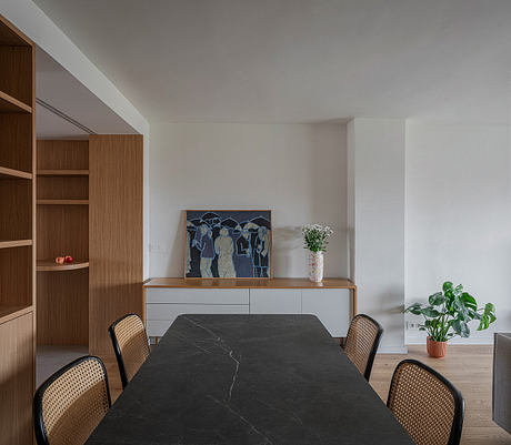 Minimalist dining area with wooden storage, marble table, and abstract art.