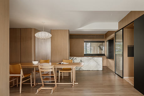 Spacious modern dining area with wood paneling, marble island, and neutral-toned decor.