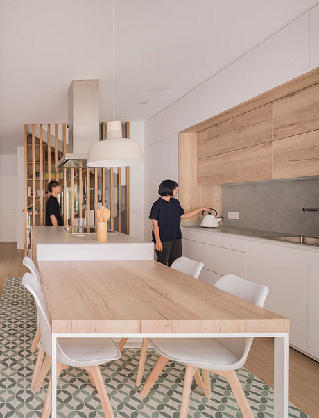 Minimal, modern kitchen with wooden cabinetry, marble backsplash, and patterned tile flooring.