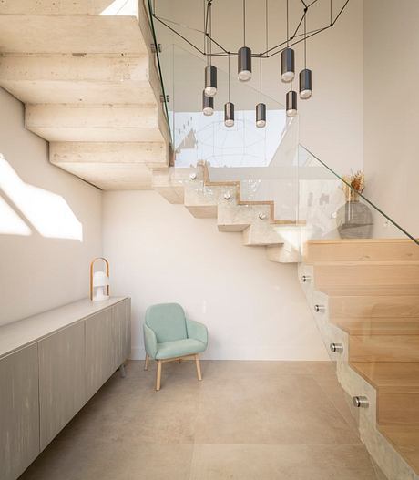 Sleek, modern staircase with suspended lighting fixtures and minimalist furnishings.