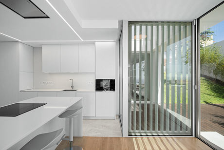 Minimalist kitchen with sleek cabinets, open to a glass-paned sliding door leading to a deck.