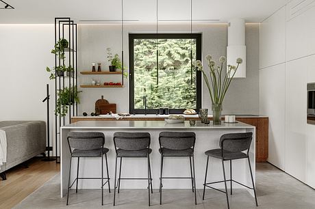 Sleek, modern kitchen with wood accents, large window overlooking lush foliage, and minimalist decor.