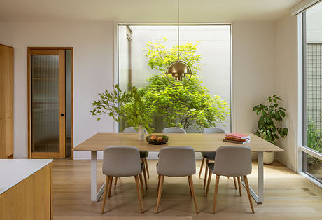 A bright, modern dining area with a large window showcasing lush greenery outside.