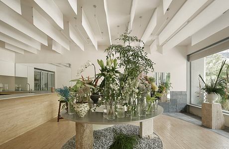 A modern, open-concept living space with a striking floral centerpiece on a round table.