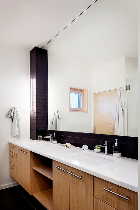 A modern bathroom with a sleek black tile column, floating vanity, and white countertop.