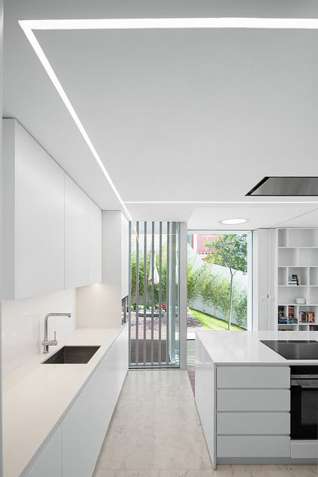 Sleek, minimalist kitchen with modern shelving, large glass door overlooking greenery.