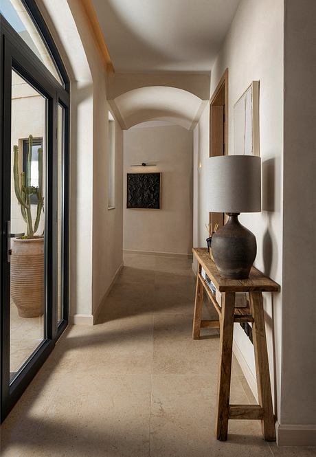 Serene arched hallway with natural wood console, textured pottery, and minimal lighting.