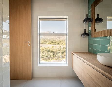 A modern bathroom with a large window showcasing a scenic natural landscape.