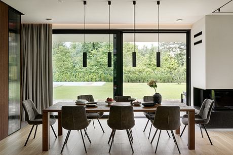 Sleek modern dining room with floor-to-ceiling windows, dark furniture, and pendant lighting.