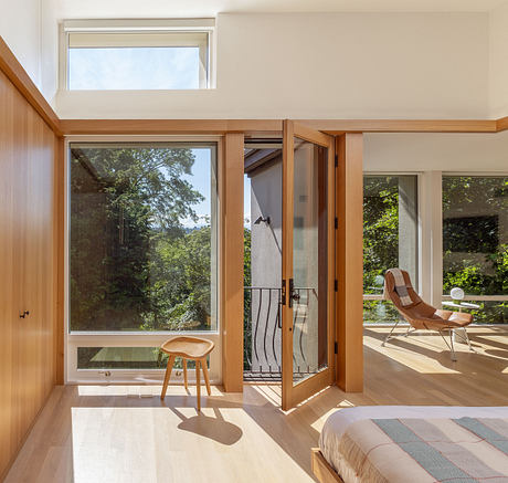 Spacious bedroom with expansive wood-framed windows overlooking lush greenery.