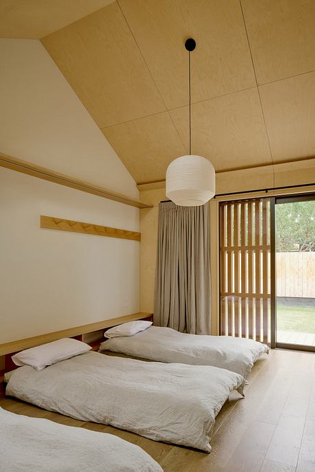 A minimalist bedroom with clean lines, wood paneling, and a spherical pendant light.