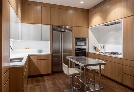 Sleek modern kitchen with wood paneled walls, built-in appliances, and a stainless steel island.
