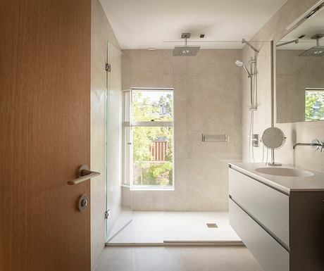 Modern, open-plan bathroom with minimalist design, large window, and sleek fixtures.