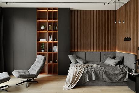 A modern, minimalist bedroom with dark-colored walls, built-in wood shelving, and a comfortable, plush sofa.