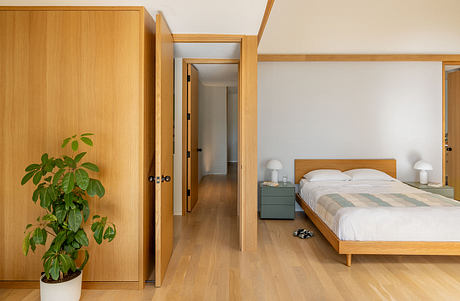 Minimalist bedroom with wooden furniture, clean lines, and potted plant.