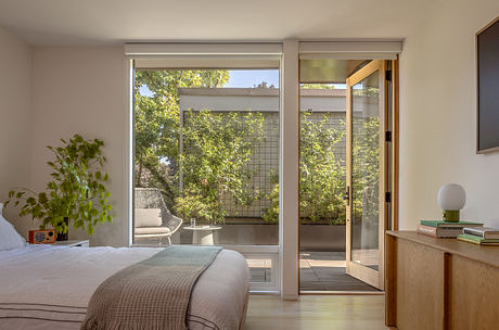A cozy bedroom with large sliding glass doors leading to a lush outdoor patio.