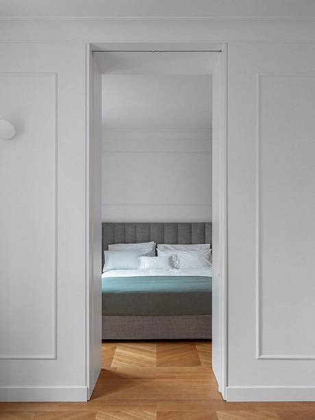 Minimalist bedroom design with clean lines, gray upholstered headboard, and hardwood floors.