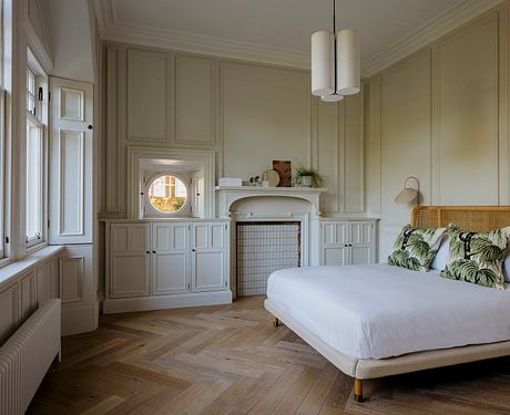 Elegant bedroom with intricate wainscoting, herringbone wood floors, and stylish lighting.
