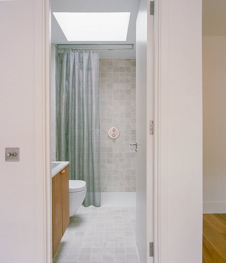 Modern bathroom interior with sleek lighting, tiled walls, and curtain-covered shower.