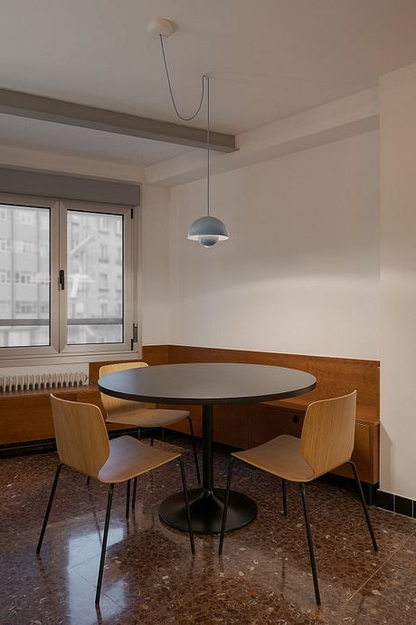 A modern dining area with a round table, wooden chairs, and a pendant light fixture.