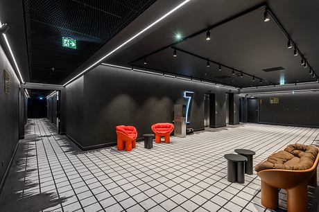 Dramatic lighting, sleek black walls, and striking red chairs create a modern, dramatic lobby.