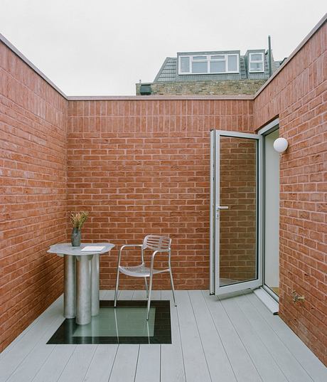 Brick walls, glass door, and modern furnishings create a cozy outdoor living space.