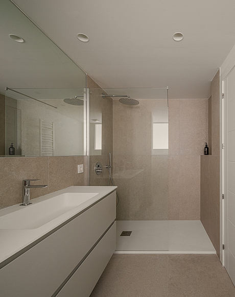 A modern bathroom with minimalist design, featuring a large vanity, shower, and clean lines.