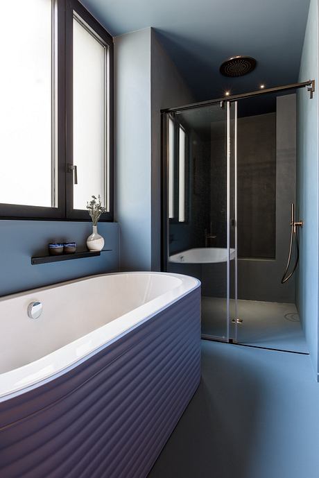 A modern bathroom with a white freestanding bathtub, glass shower enclosure, and dark accents.