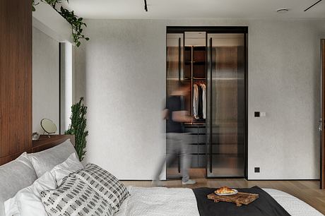 Minimalist bedroom with a sleek, glass-enclosed wardrobe and lush indoor plants.