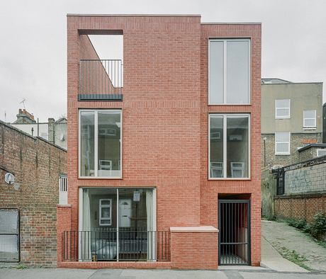 A modern, multi-story brick building with large windows and a balcony.