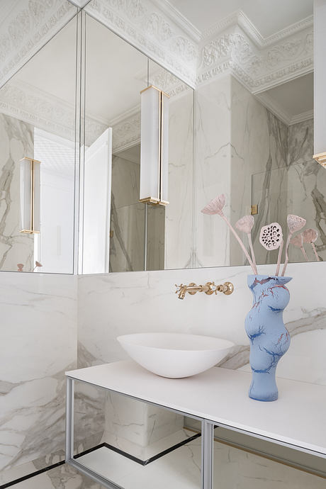 Elegant marble bathroom with intricate ceiling moldings and modern vanity fixtures.