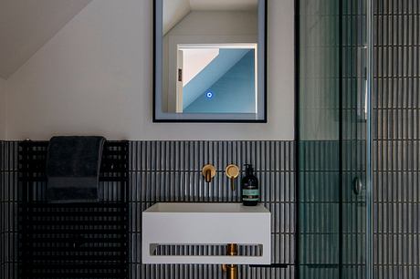 Contemporary bathroom with sleek black and white design, recessed lighting, and geometric tile patterns.