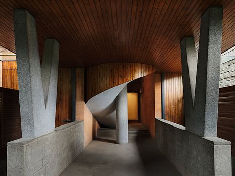 A striking wooden ceiling with curved concrete walls, creating an architectural passage.