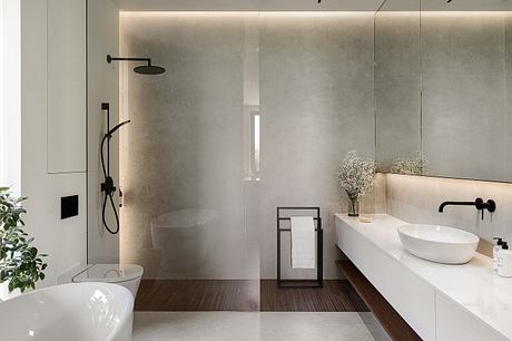 A modern bathroom with sleek, minimalist design featuring a glass shower, vessel sink, and warm lighting.