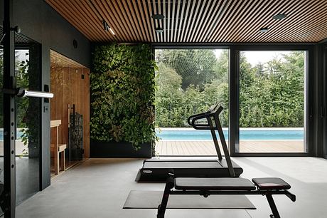 Sleek modern gym with lush green wall, expansive windows, and pool view.