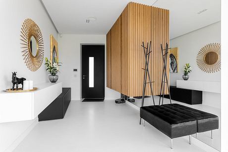 Minimalist interior with wooden accent wall, sleek black furniture, and decorative mirrors.