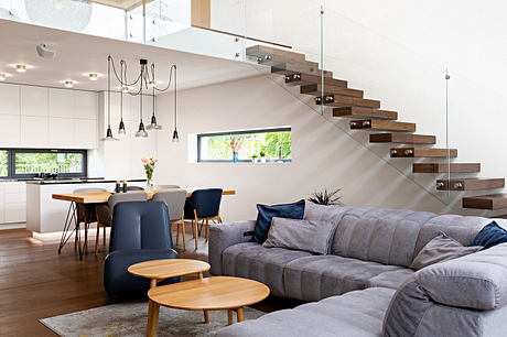 Contemporary open-concept living area with floating wooden stairs, minimalist decor.